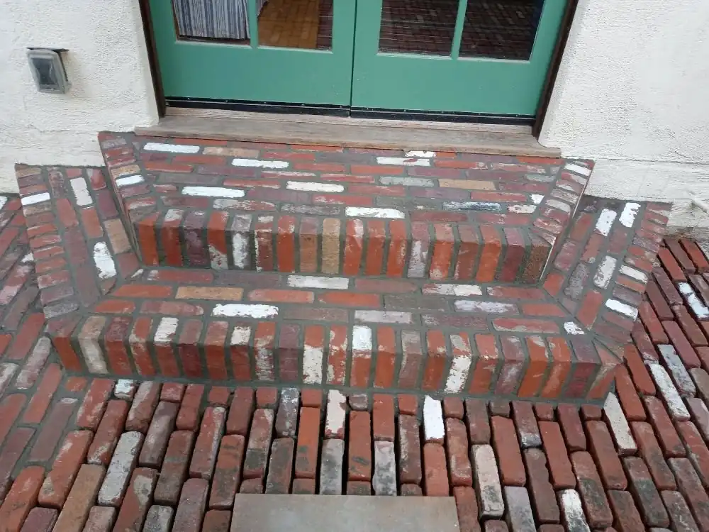 Used brick steps and landing, freshly grouted, at a green double door