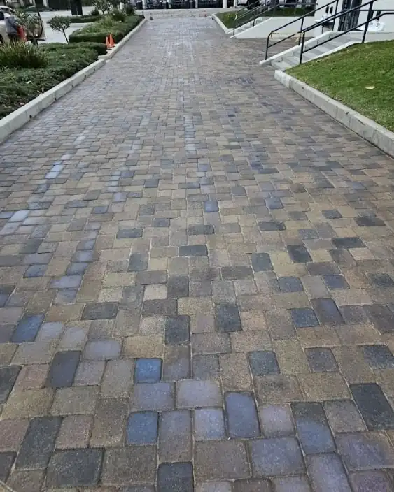A long cobble paver driveway in mixed warm tones leading to a garage